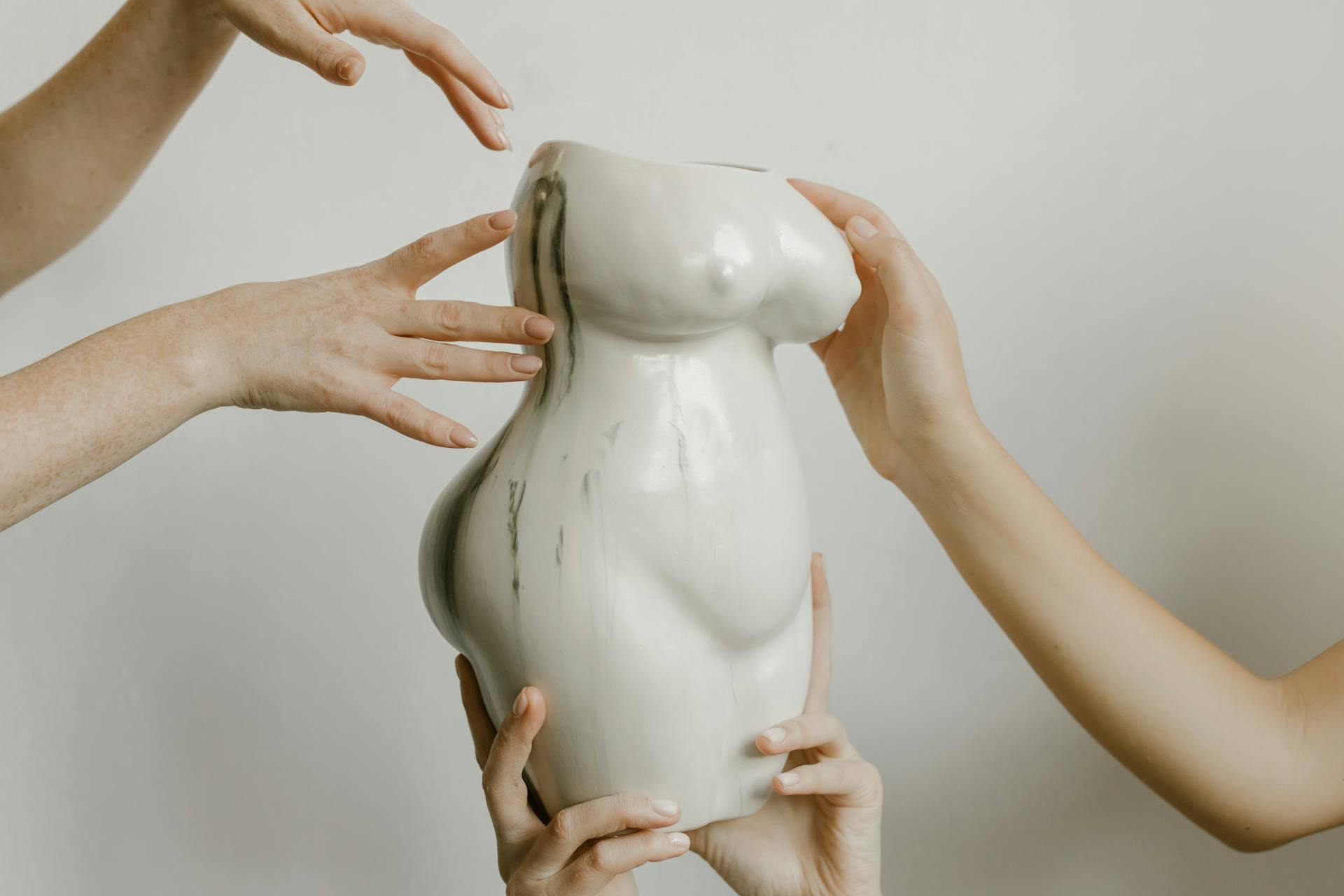 Clay figurine woman's changing body supported by hands